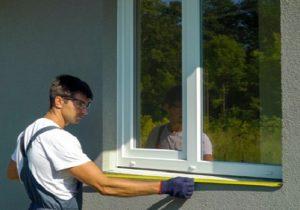 A window installer measuring the exterior of a window.