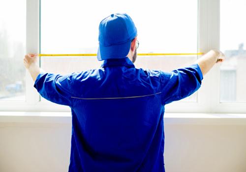 Worker dressed in blue, measuring window frame and getting ready for Window Replacement in Glen Ellyn IL