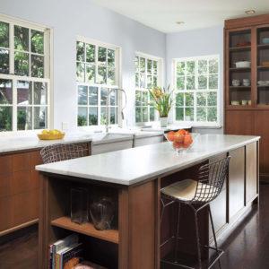 A brightly lit kitchen with windows lining the wall and a beautiful kitchen island