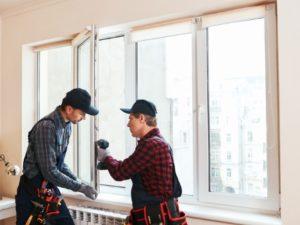 Two window installers work together to install new replacement windows. 