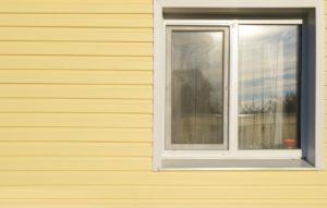 close-up of yellow house siding with vinyl windows